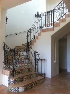 a stair case with wrought iron railing and handrails in a home entryway