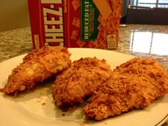 fried chicken on a plate next to a carton of cheetos