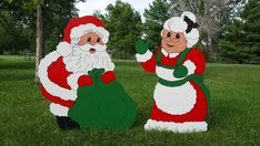 two santa clause statues sitting in the grass