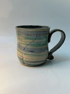 a striped coffee cup sitting on top of a white table