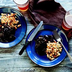 two blue plates topped with food next to glasses of beer