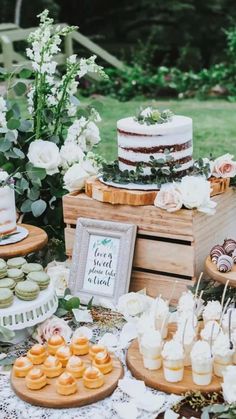 a table topped with cakes and cupcakes on top of wooden boxes filled with flowers