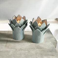 two blue vases with candles in them sitting on a table