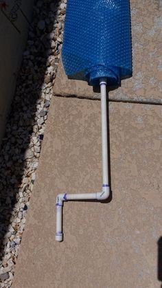 a blue toilet sitting on top of a cement floor next to a drain faucet