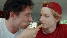 two men are eating food together in a room