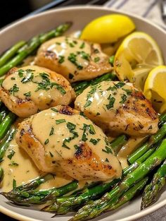 chicken and asparagus with lemon sauce in a white bowl on top of a table