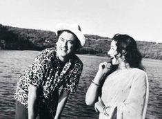 two women standing next to each other on a boat in the water and one is wearing a hat