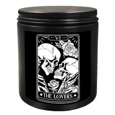 a black candle with two skulls and roses on the front, sitting next to a white background