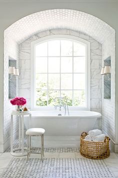 a white bath tub sitting under a window in a bathroom