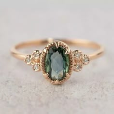 a ring with an oval green stone surrounded by small white and brown diamonds on top