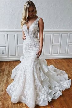 a woman in a white wedding dress standing on a wooden floor next to a wall