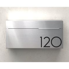 a stainless steel wall mounted address sign with the number 120 on it's side