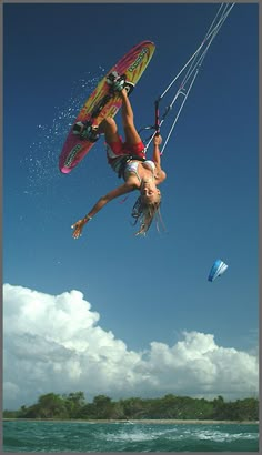 a person on a surfboard is in the air above the water with a parachute