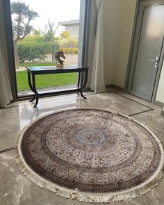 a large round rug on the floor in front of a glass door with an open window