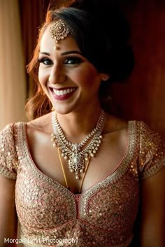 a smiling woman in a bridal outfit with jewelry on her neck and headpiece