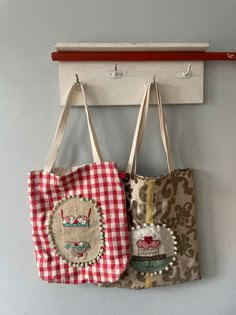 two purses hanging from hooks on a wall