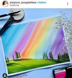 an image of a rainbow painting on a piece of paper next to a cell phone