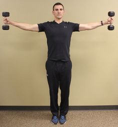 a man standing in front of a wall holding two dumbbells