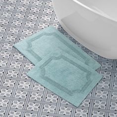 two blue towels sitting on top of a bathroom floor next to a bathtub and toilet