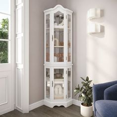 a white corner cabinet with glass doors in a living room next to a blue couch