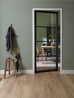 an open door leading to a dining room with green walls and wood flooring on the side