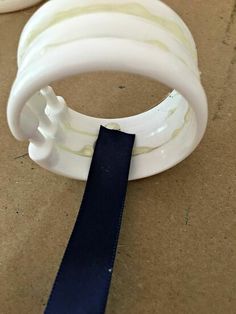 a close up of a plastic object with a ribbon around it's end and another piece of material in the background