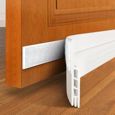 a close up of a white door handle on a wooden door with wood grained flooring