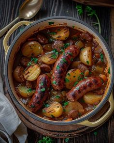 a pot filled with sausage and potatoes on top of a wooden table