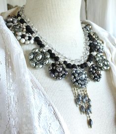 "This stunning silver / gray statement necklace is made with vintage clip on earrings.  What a gorgeous formal piece this is, (thinking Mother of the Bride), a low cut evening or cocktail dress, or even a crisp white blouse with blue jeans.  The silver/gray look is eye catching.  The earrings are on bails in order to string them with black polished lava beads, and intermittent crystal rondels. The clear glass beaded chain above it is a beautiful complement to this head-turning necklace. Total po Elegant One-of-a-kind Wedding Jewelry, Handmade Glamorous Silver Jewelry, Elegant Gray Beaded Jewelry, Elegant Gray Necklace For Evening, Elegant Gray Jewelry For Evening, Handmade Elegant Gray Jewelry, Handmade Gray Elegant Jewelry, Elegant Handmade Gray Jewelry, Elegant Gray Necklace For Wedding