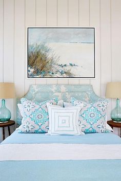 a bed with blue and white comforter in a bedroom next to two lamps on either side of the bed