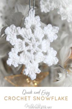 a white crocheted snowflake ornament hanging from a tree branch