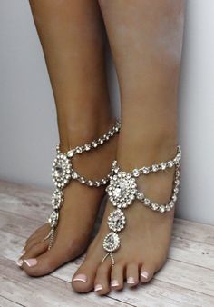 Katy Barefoot Sandals can only be described in one word: exquisite. This stunning foot jewelry features over 200 individual rhinestones which vary in size and adorn this pair. Handmade using silver shade, Katy Sandals are also available in gold and rose gold. The centerpieces are carefully connected together, while rhinestone embedded Kundan chain runs along the side of the sandals. The back of the sandals feature comfortable lobster clasp and an adjustable 2 inch closure. Wear these gorgeous sa Elegant Silver Anklets With Bling, Elegant Silver Bling Anklets, Silver Crystal Sandals For Evening, Silver Crystal Sandals, Silver Crystal Sandals For Party, Elegant Barefoot Sandals For Party, Elegant Silver Barefoot Sandals For Party, Elegant Silver Toe Ring Barefoot Sandals, Silver Sandals With Bling And Ankle Strap