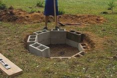 a man standing next to a fire pit in the middle of a field