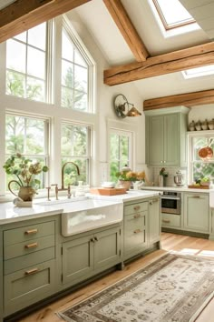 a kitchen filled with lots of green cabinets and white counter tops next to a window