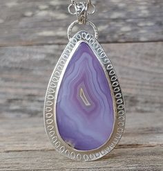 "Breathtaking Agua Nueva Agate sterling silver metalwork pendant necklace.  The stone features the most amazingly vibrant shades of purple to lavender with a full fortification pattern.  It has been hand stamped. This is a big statement pendant necklace that will surely get noticed! It comes with a substantial 5mm sterling silver rollo chain finished with a lobster claw clasp and amethyst briolette. The pendant measures 3\" long from the top of the bail and  x 1 1/2\"W. The chain measures 18\" l Unique Purple Teardrop Jewelry, Handmade Lavender Teardrop Jewelry, Unique Purple Necklace With Large Pendant, Artisan Drop Gemstone Necklace, Handmade Purple Teardrop Pendant Jewelry, Purple Teardrop Bohemian Necklace, Bohemian Purple Teardrop Necklace, Artisan Teardrop Necklace With Large Pendant, Artisan Teardrop Necklace With Large Stone