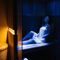 a woman sitting on a bed in a room with blue light coming through the window