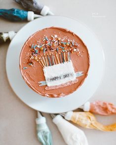 a birthday cake with candles on it sitting on a plate next to other decorations and confetti