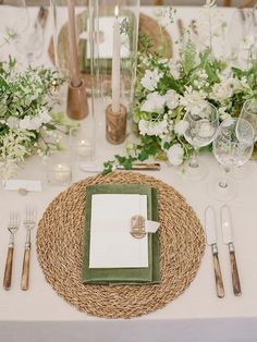 a table with place settings, silverware and greenery on the tablescloths