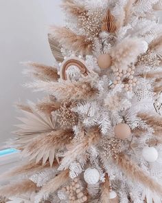 a white christmas tree decorated with feathers and ornaments