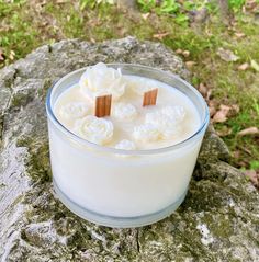 a glass container filled with white flowers sitting on top of a rock