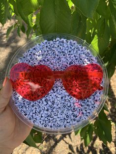 a hand holding up a bowl with red sunglasses on it and blue speckles