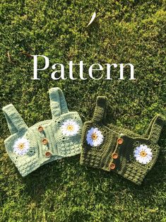 three crocheted mittens and gloves sitting on the grass with daisies in them