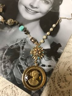 This is a vintage assemblage upscaled cameo necklace. I started with a vintage gold tone to yellow iridescent cameo and added it to a tiny Sunburst pin, which I upscaled.  It was missing some sets so I did replace them with different faux pearls and turquoise rhinestones. It does not have all of the exact pattern of stones that it started with but it still looks great !  On one side of the necklace is some vintage faux pearl rosary beads combined with different gold tone chains. The opposite sid Vintage Costume Jewelry Medallion Necklace, Vintage Medallion Costume Jewelry Necklace, Heirloom Handmade Vintage Necklace, Vintage Cameo Medallion Necklace, Gold Cameo Jewelry For Vintage Events, Vintage Cameo Necklaces For Vintage Events, Vintage Cameo Necklace For Vintage Events, Vintage Antique Gold Medallion Necklace, Unique Vintage Charm Necklaces