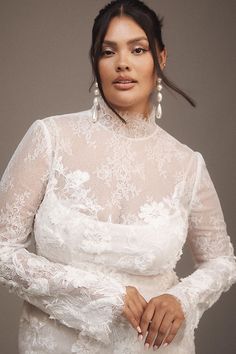 a woman in a white dress with long sleeves and pearls on her head is posing for the camera