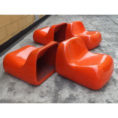 three orange chairs sitting on top of cement