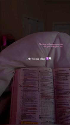 an open book sitting on top of a bed next to a pink comforter and pillow