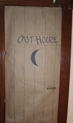 a door with the words out house written on it and a crescent moon painted on it