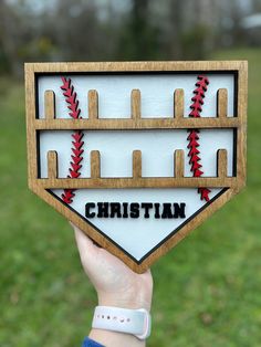 a person holding up a wooden sign with baseballs on it and the word christian