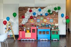 a birthday party with balloons and decorations on the wall, including a train cake stand