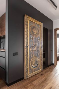 an ornate wooden door in the middle of a room with wood floors and black walls